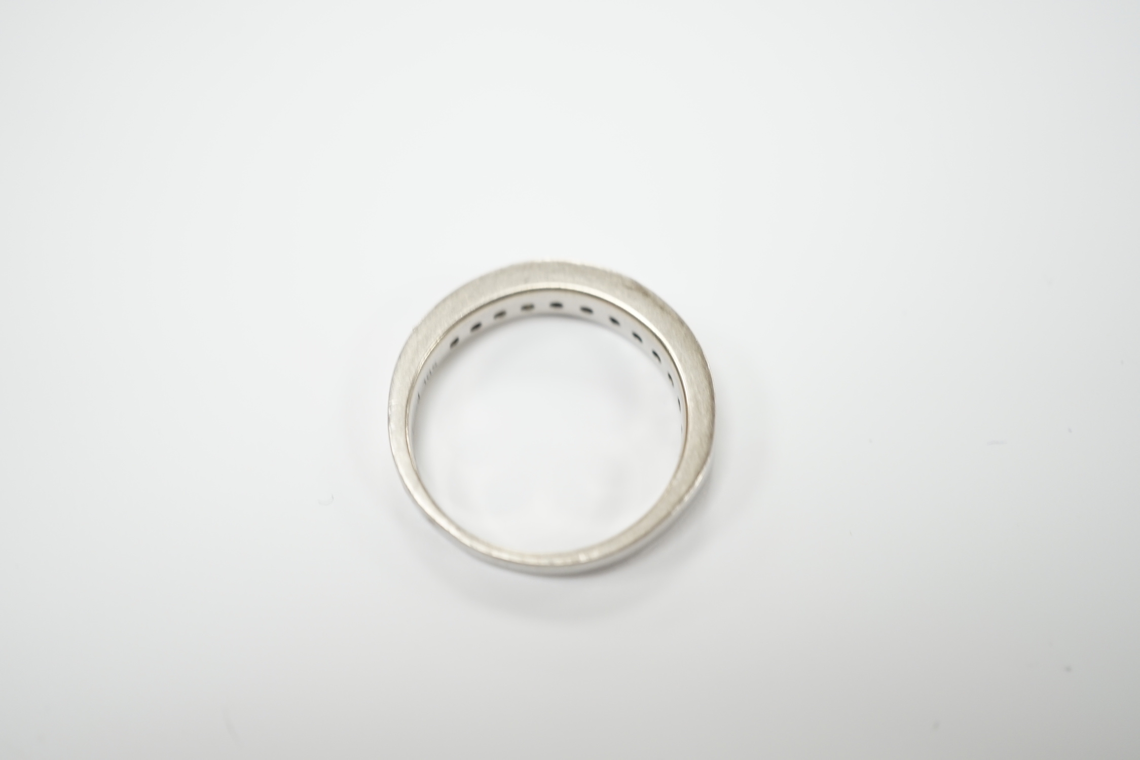 A white metal (engraved PT 950) and channel set twelve stone diamond half eternity ring, size N/O, gross weight 6.7 grams.